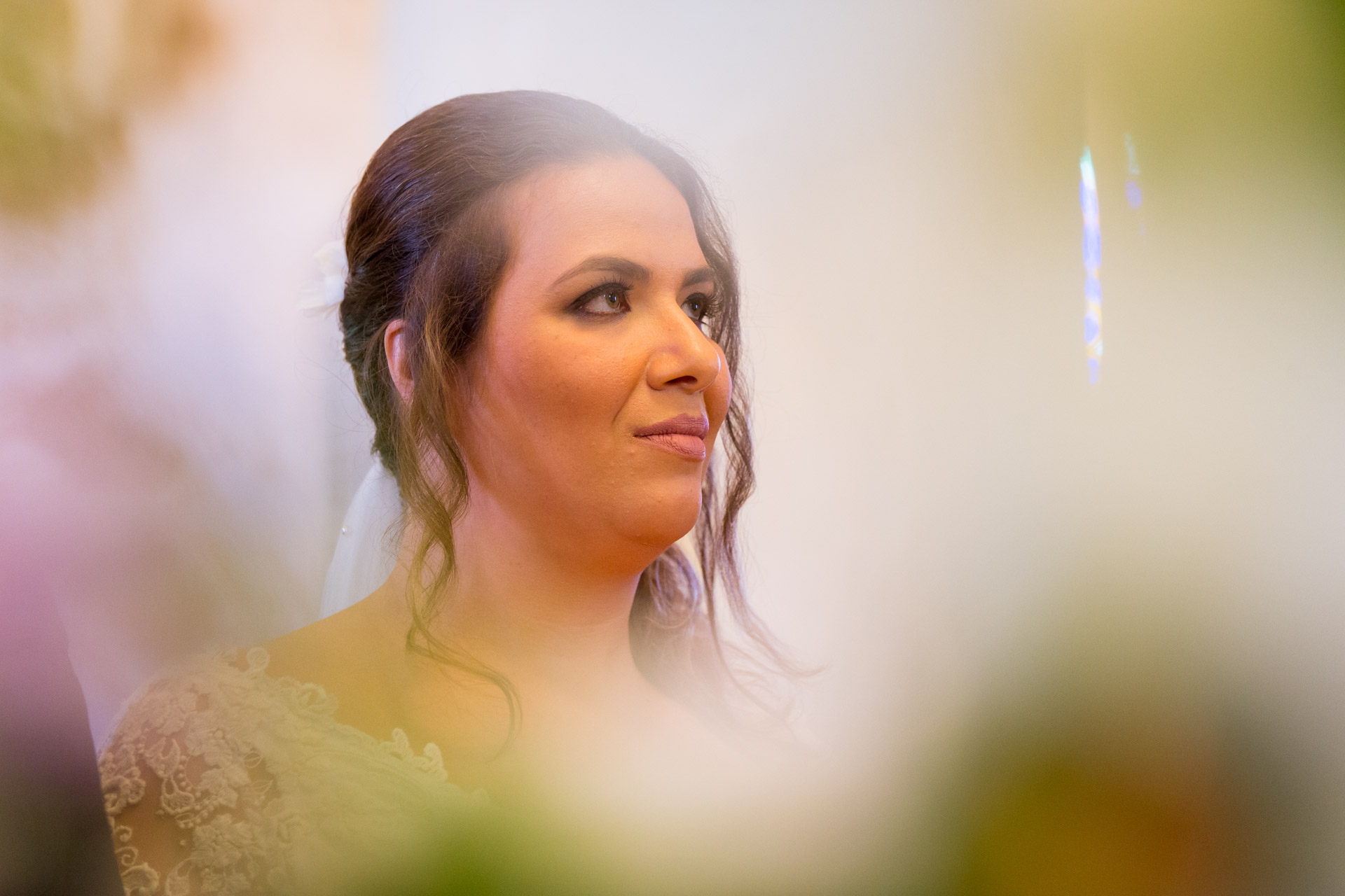 portrait de la mariee dans l'eglise avec les fleurs en premier plan